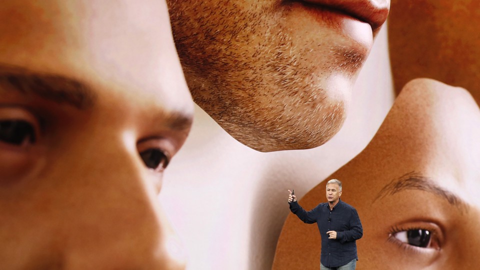 Phil Schiller stands in front of a screen displaying images of disembodied faces.