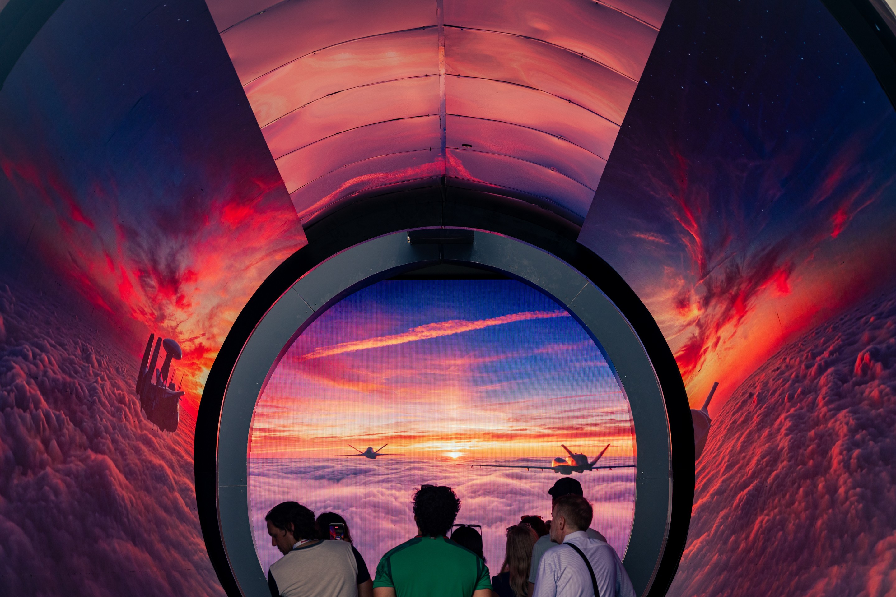 people look at a display of planes in a sunset