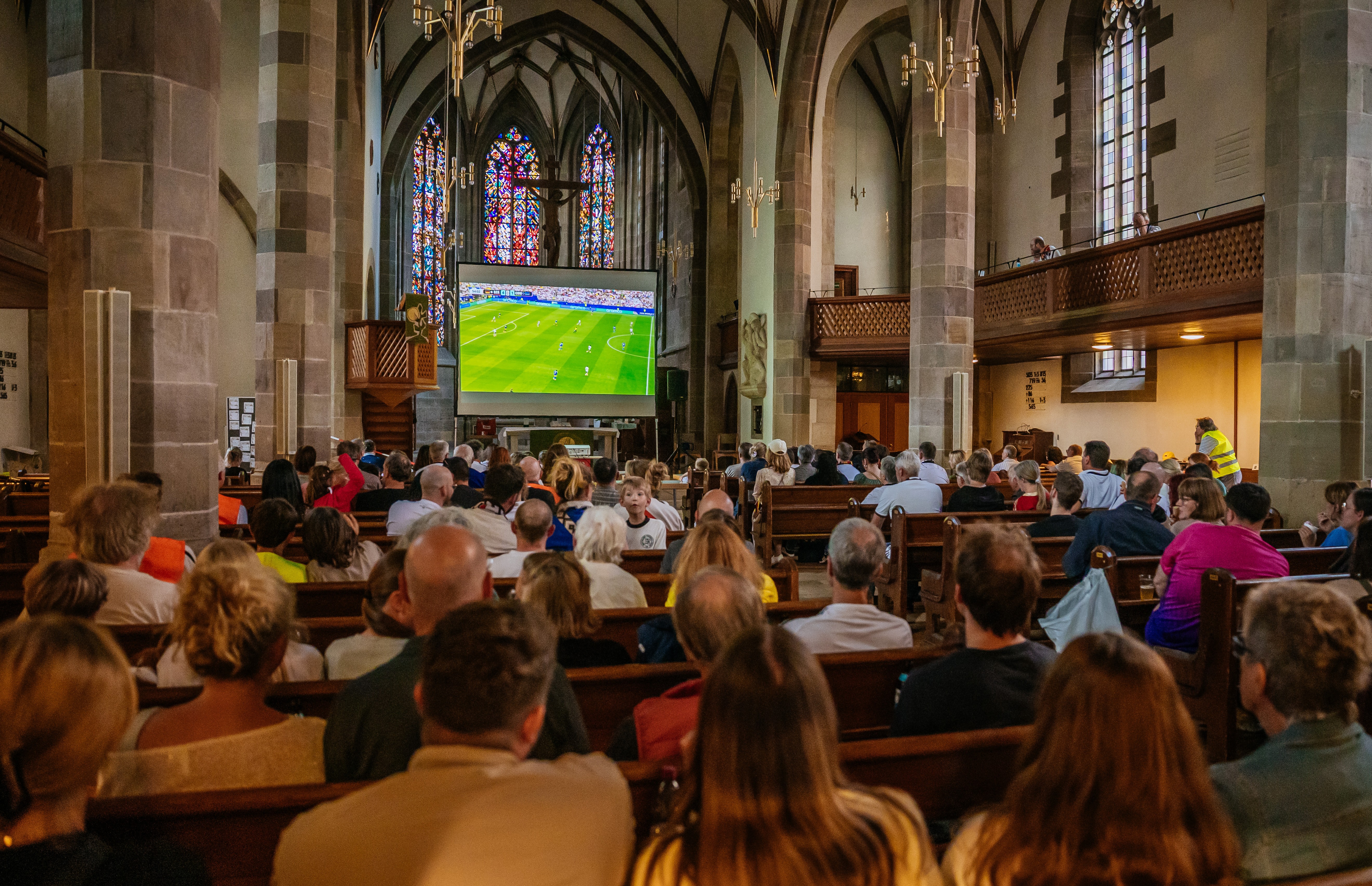 Football fans watch a match on a screen inside a church.