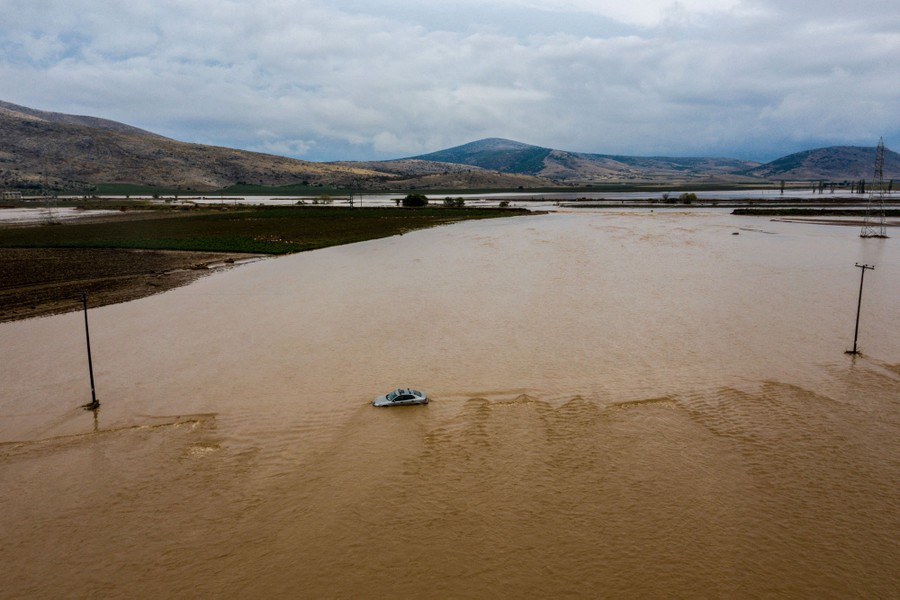 A broad view of a flooded plain and road, with a single car stranded in the water.