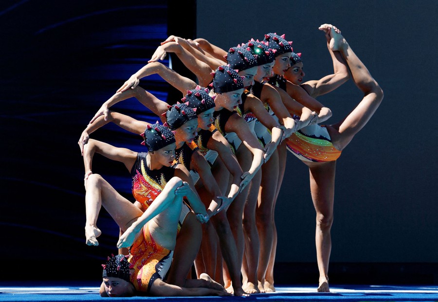 Nine swimmers pose together, making an elaborate shape, before their performance.