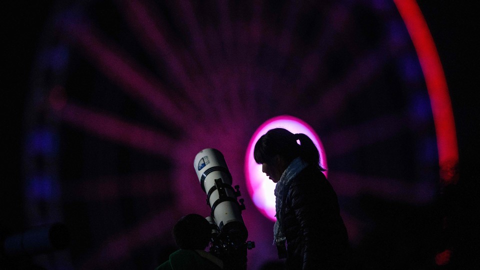 A woman and child use a telescope to explore the night sky
