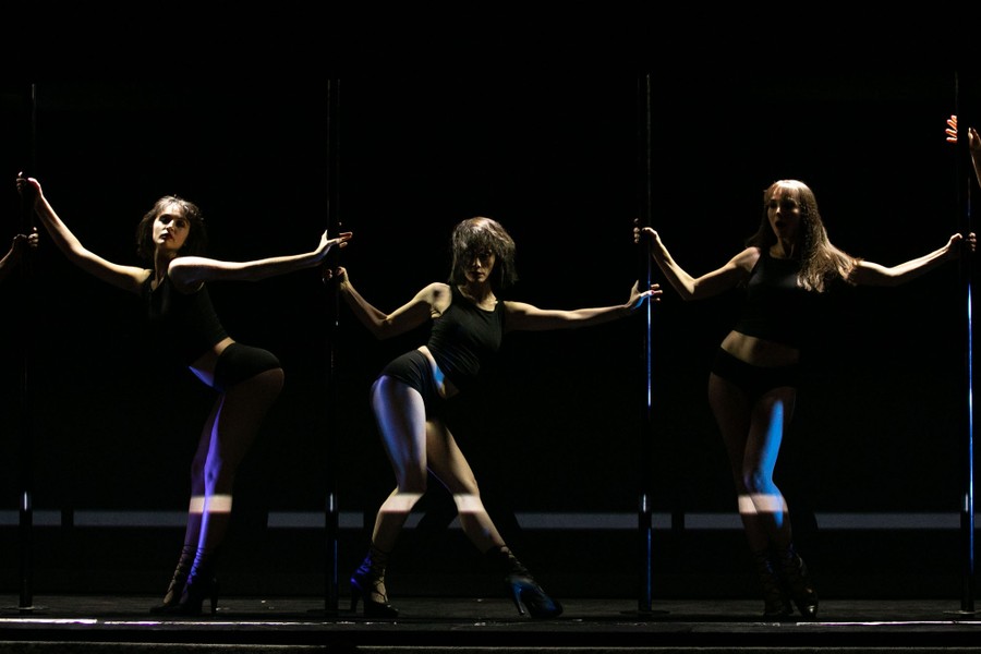 Three women dance on a dark cabaret stage.