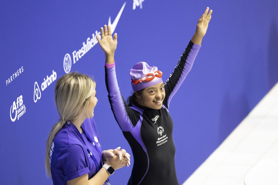 A swimmer raises their arms and. smiles before a race.
