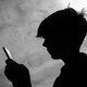 A black-and-white photograph shows a teenage boy looking at a smartphone.
