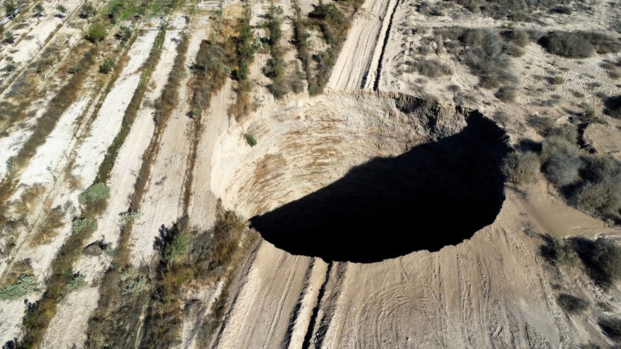 An aerial view of a large sinkhole in a desert area