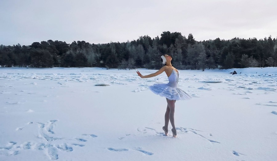 A ballerina dances on a snow-covered body of water.