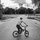 a black and white photograph of a teen boy on a bike near a water tower