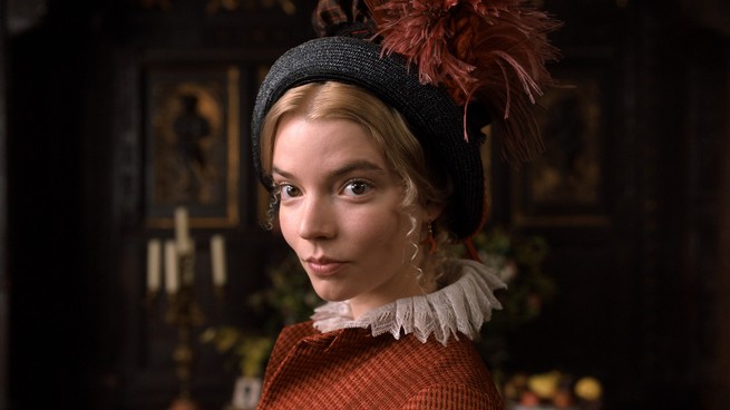 Emma, wearing a feathered bonnet, looks at the camera