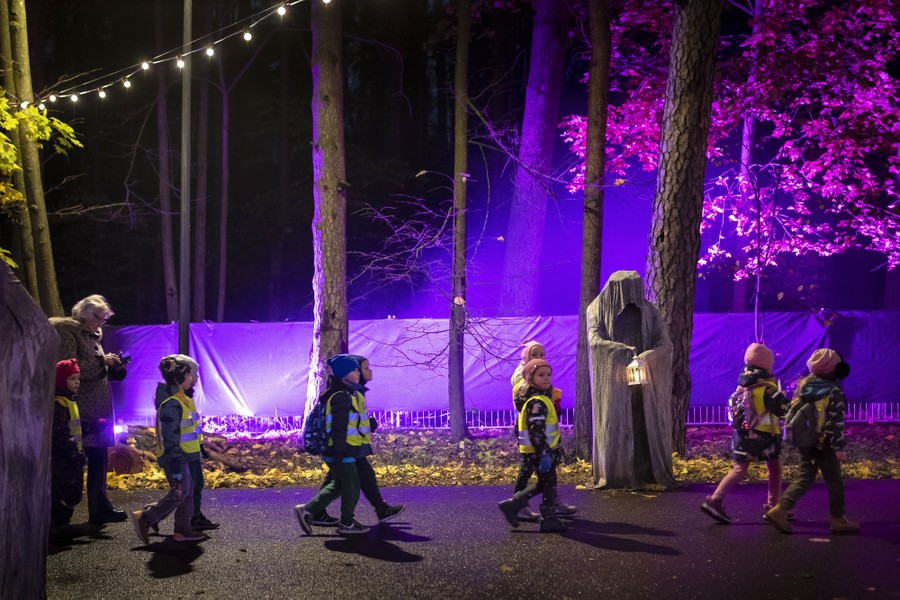 Children walk in pairs past spooky decorations.