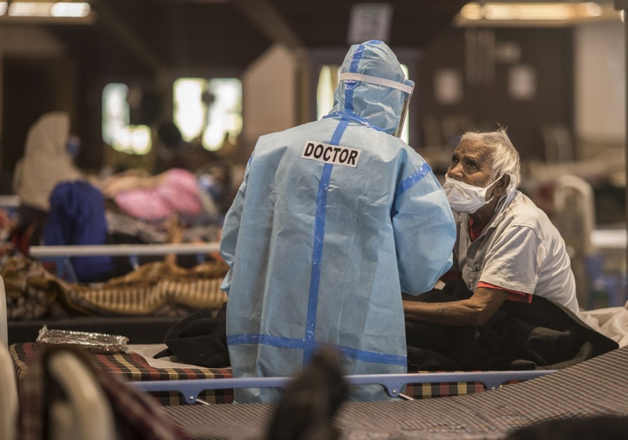 A doctor in protective gear visits with a patient in a temporary clinic.