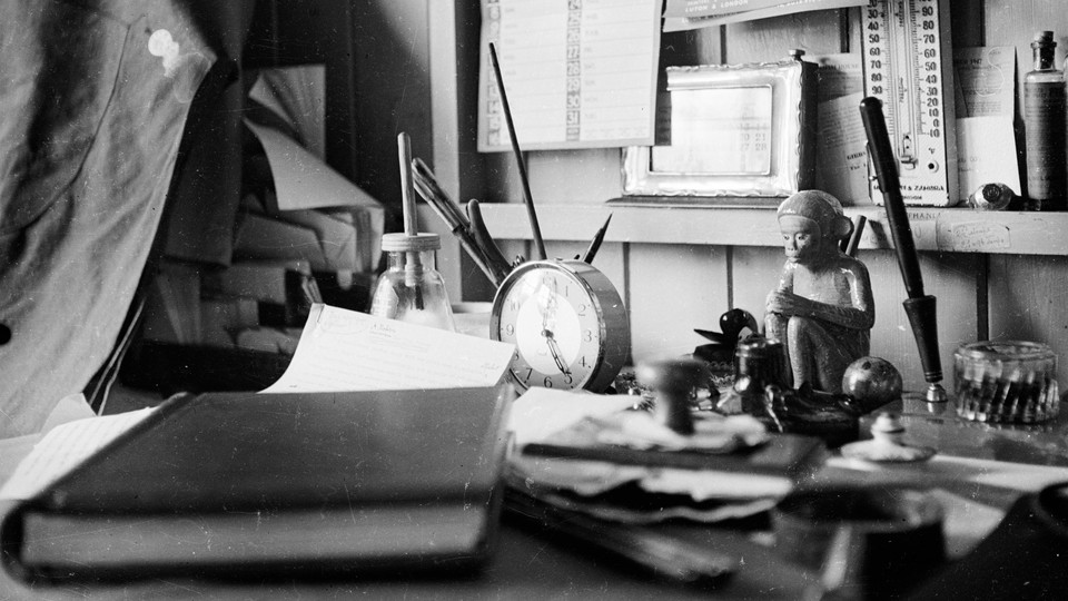 A black-and-white photo of a desk covered in personal effects