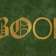 The word "book" embossed in foil letters on a green leather background. The first two letters are embellished Gothic fonts and the last two are modern, skinny sans serifs.
