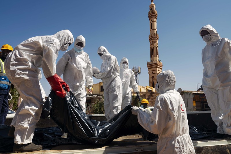 Workers recover a corpse in a body bag

