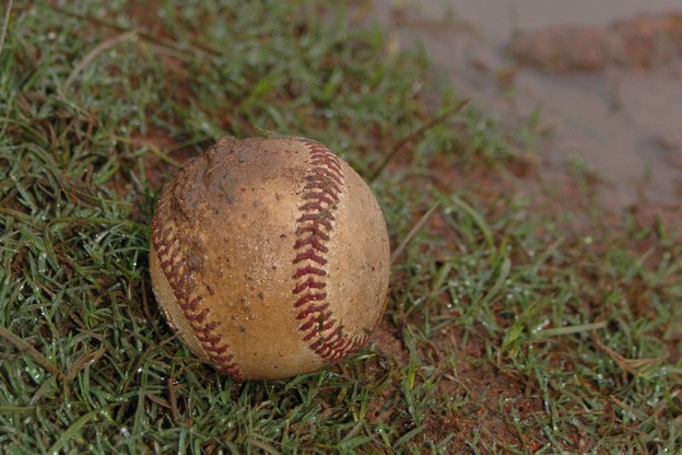 A baseball in a muddy field