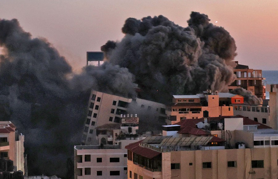 Smoke billows from an Israeli air strike as a large building falls.