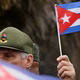 A man in a CDN cap holds a Cuban flag