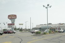 A giant parking lot outside a restaurant; a large red sign reads "Frisck's Big Boy Drive Thru: Pick up a whole coconut cream pie"