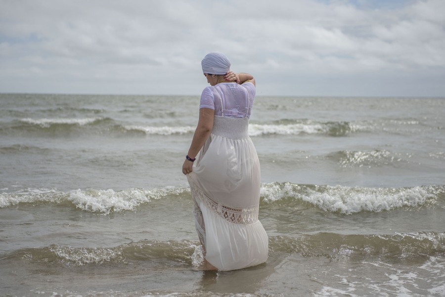 A woman in a white dress stands among small waves.