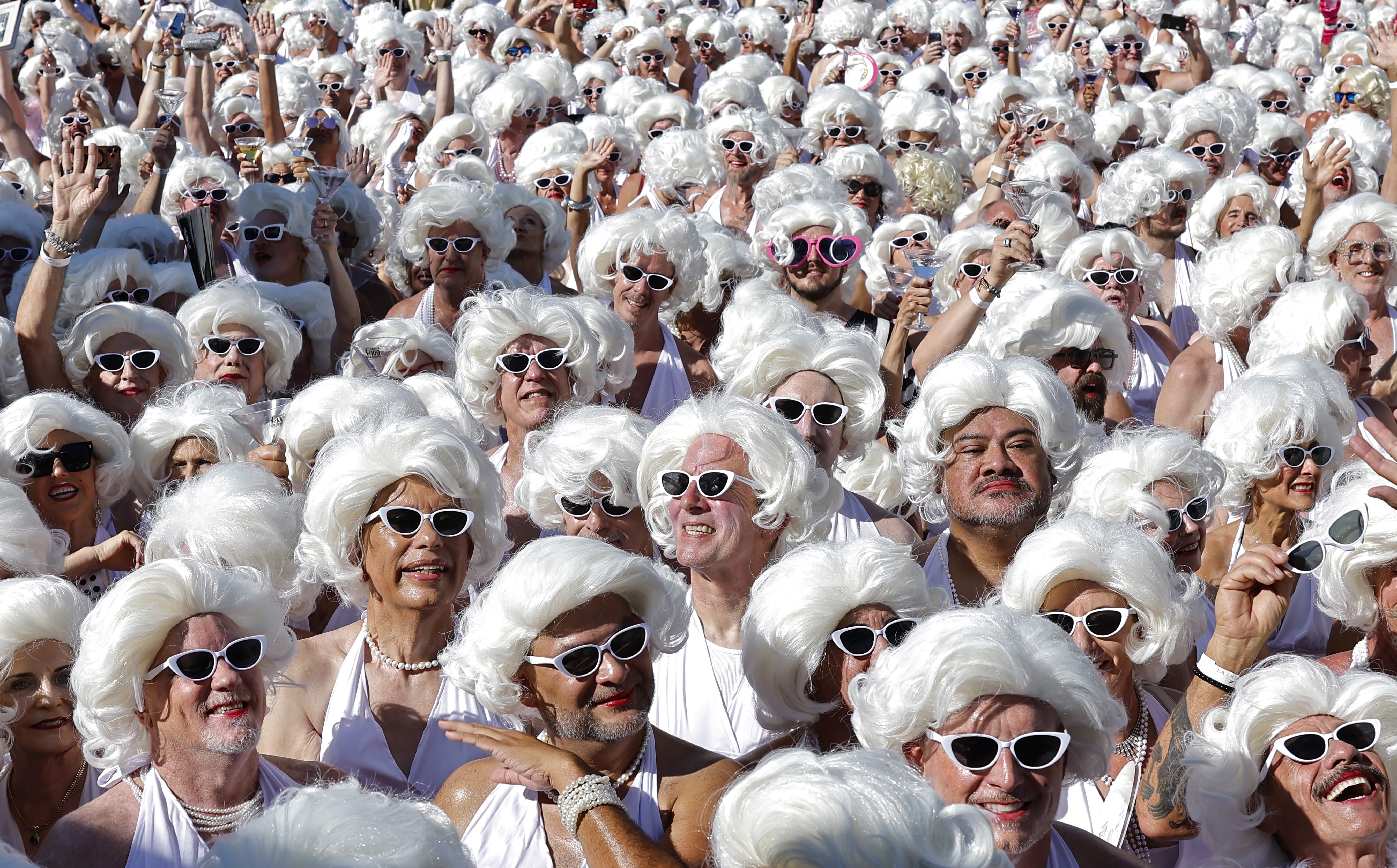 A crowd of dozens of people dressed as Marilyn Monroe, wearing white wigs and sunglasses