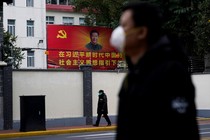 People wearing masks walk past a portrait of Chinese President Xi Jinping.