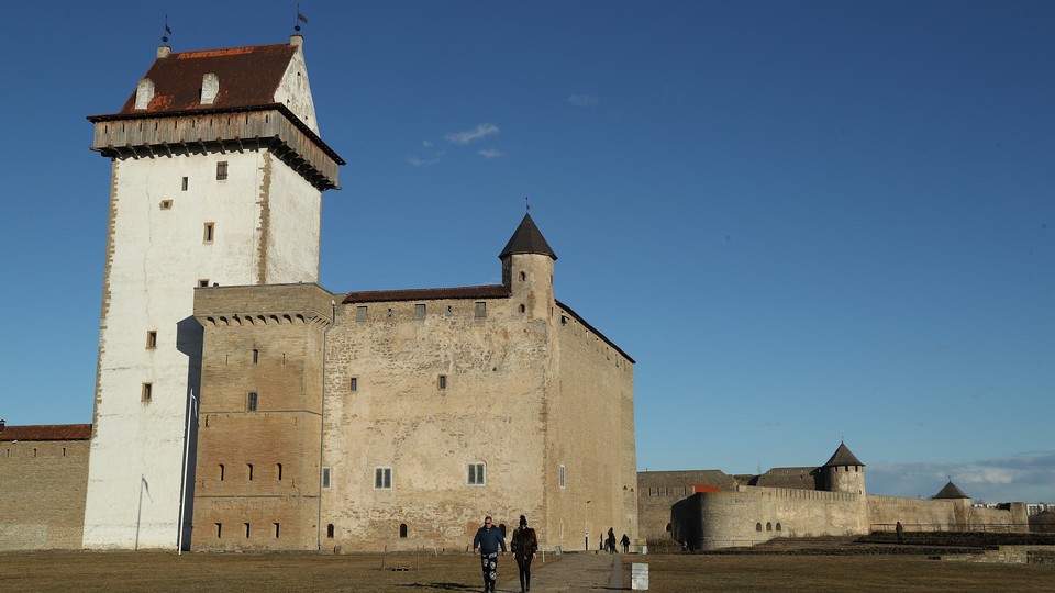 Visitors walk on the grounds of Narva's Hermann Castle, which is separated from Russia's Ivangorod Fortress behind it by the Narva River.
