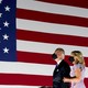 Joe and Jill Biden, masked, look at the American flag.