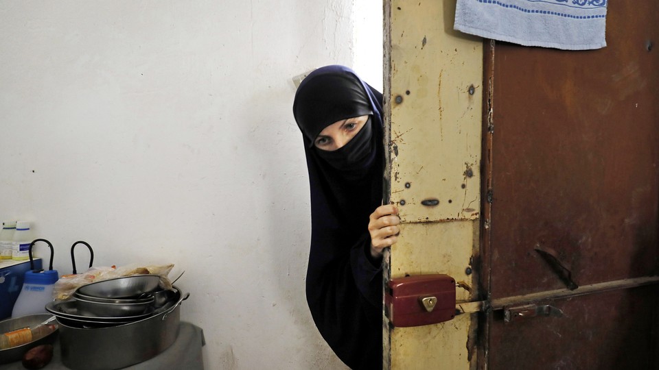 A woman whose family members are accused of being Islamic State militants enters a guarded building at a temporary camp for displaced people near the northern Syrian village of Ain Issa in 2017.