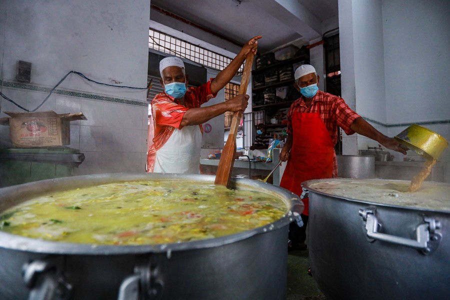 Men cook large batches of porridge.