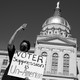 People hold up signs to protest voter suppression.
