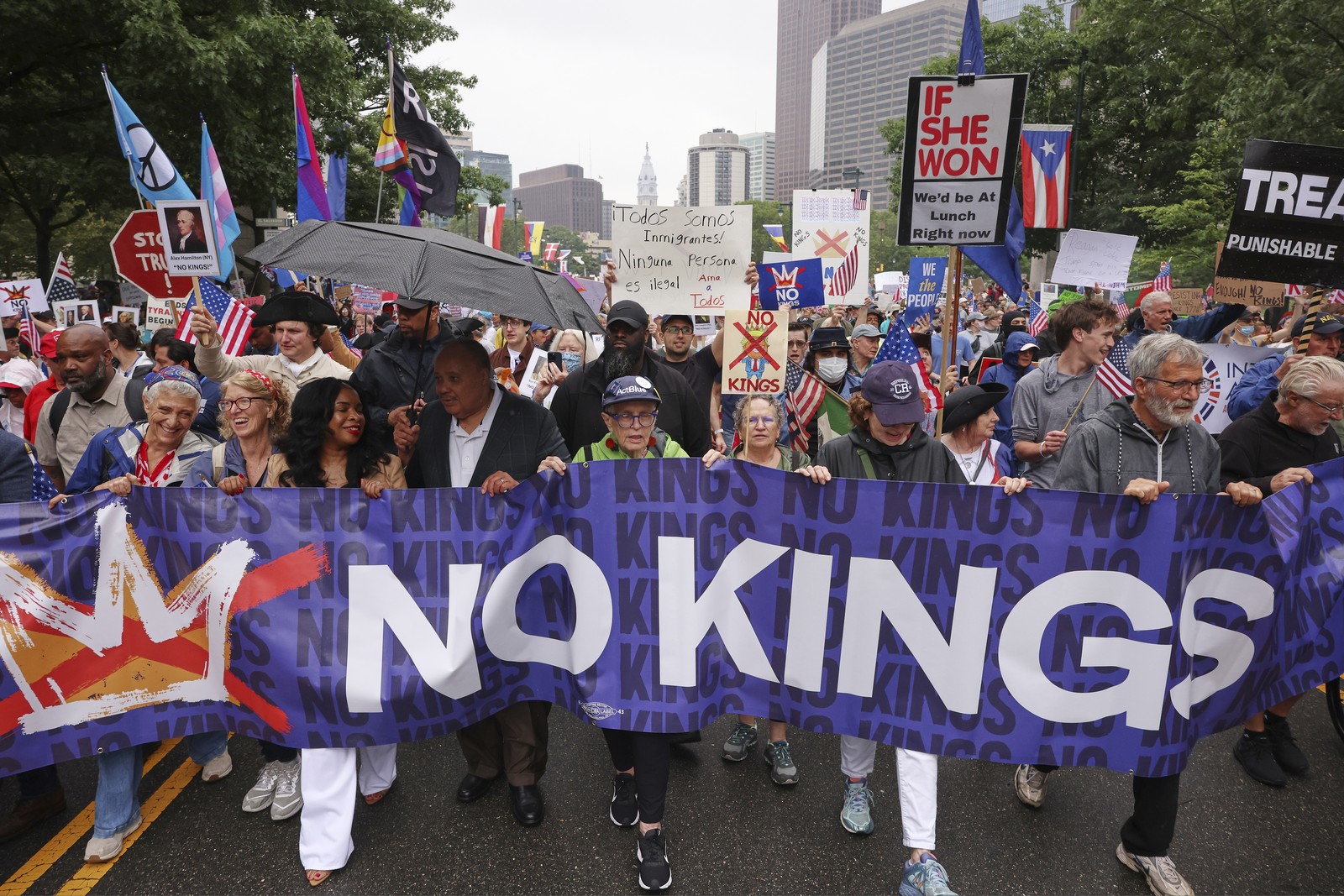 Protesters march down a street, carrying a banner that reads 