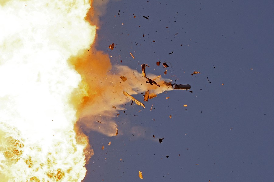 An unmanned aerial vehicle explodes into pieces and a fireball in the sky.