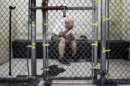 A man in a jail cell with his head in his hands