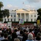 People gather with signs outside the White House.