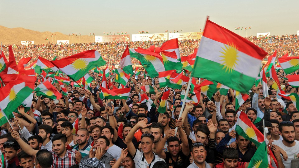 Kurdish people attend a rally and wave Kurdish flags.