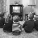 A black-and-white photo of children watching television