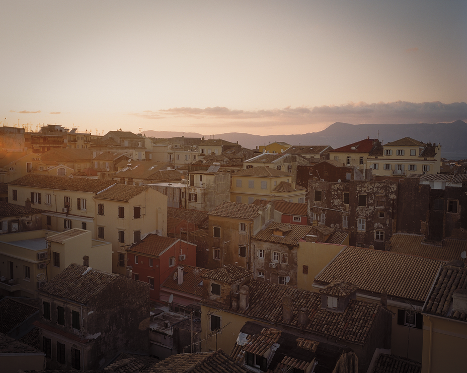 sunset photo looking out over crowded buildings with hills on the horizon