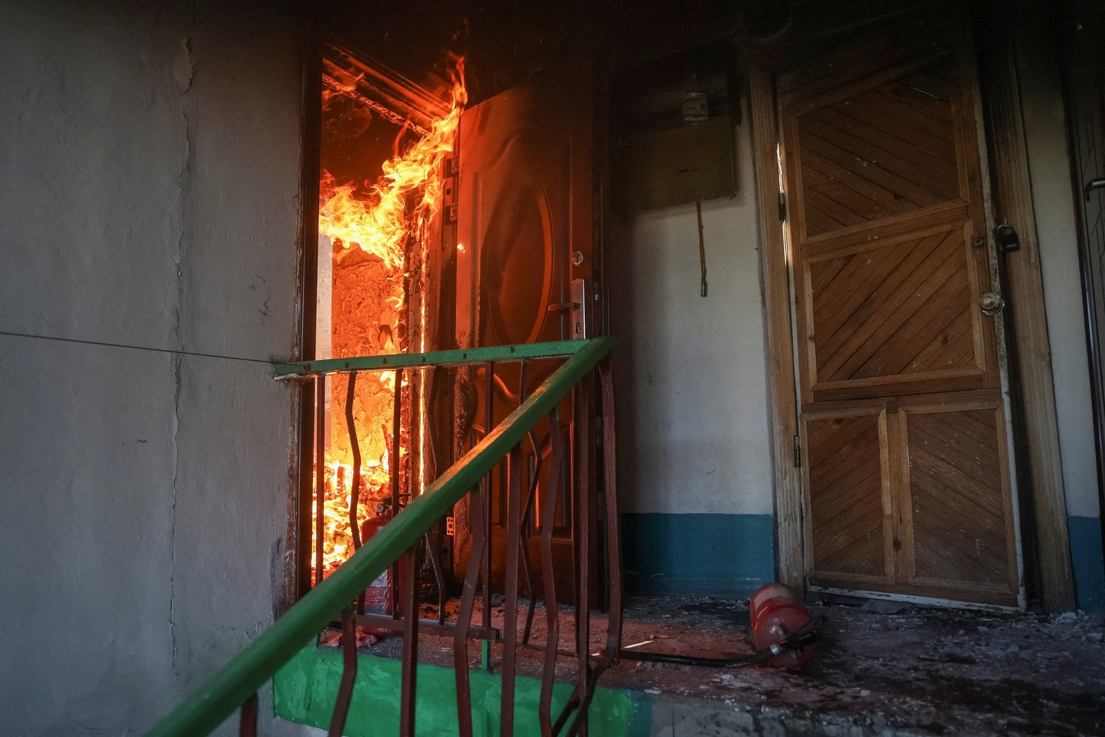 A fire burns inside a residence, seen through an open door.