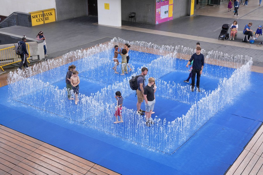 People play in a public fountain.