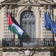 Photo of a Palestine flag and European Union flag waving on the face of a building