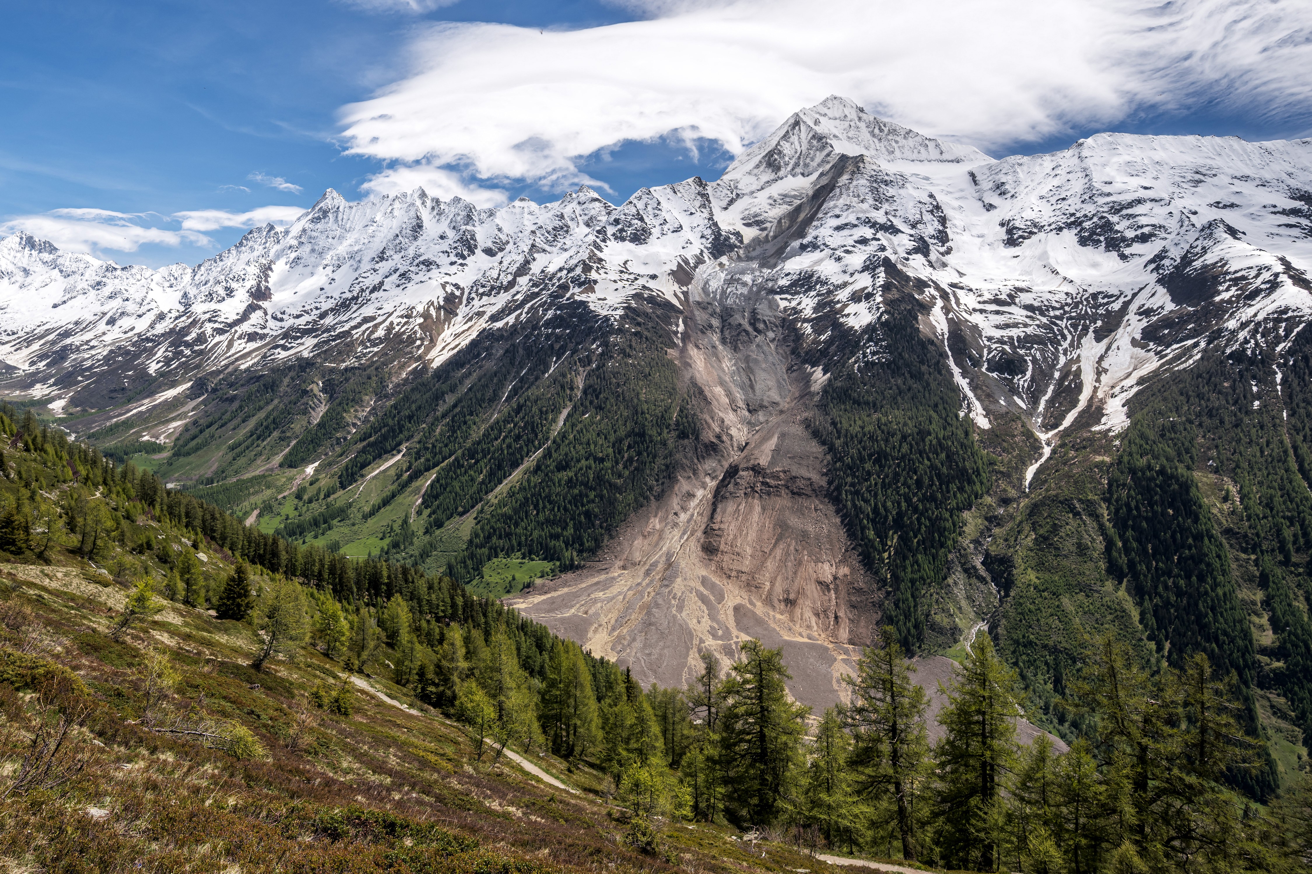 A view of the side of a broad Alpine valley, scarred by a recent landslide