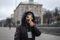 A religious woman holds a cross as she prays on Independence Square in Kyiv.