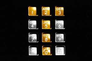 A phone dial with the buttons creating a T colored gold and the others colored silver, with a black background