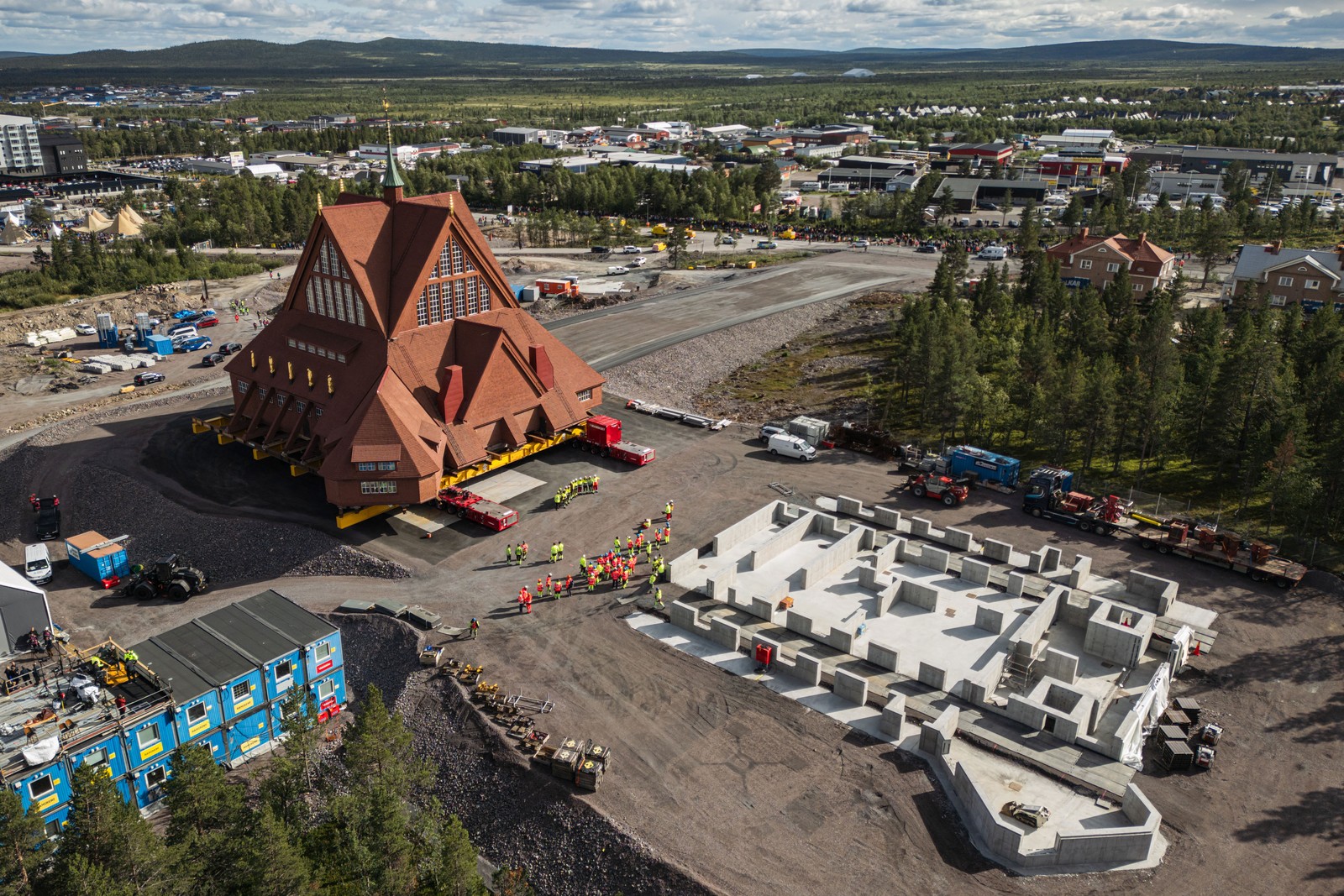 An aerial view of a church that is being moved as it approaches a newly-poured concrete foundation.