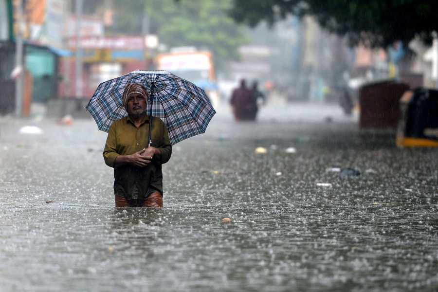 A man with an umbrella walks through a flooded street.