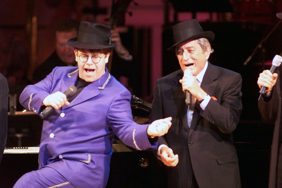 Elton John and Tony Bennett sing together on a stage.