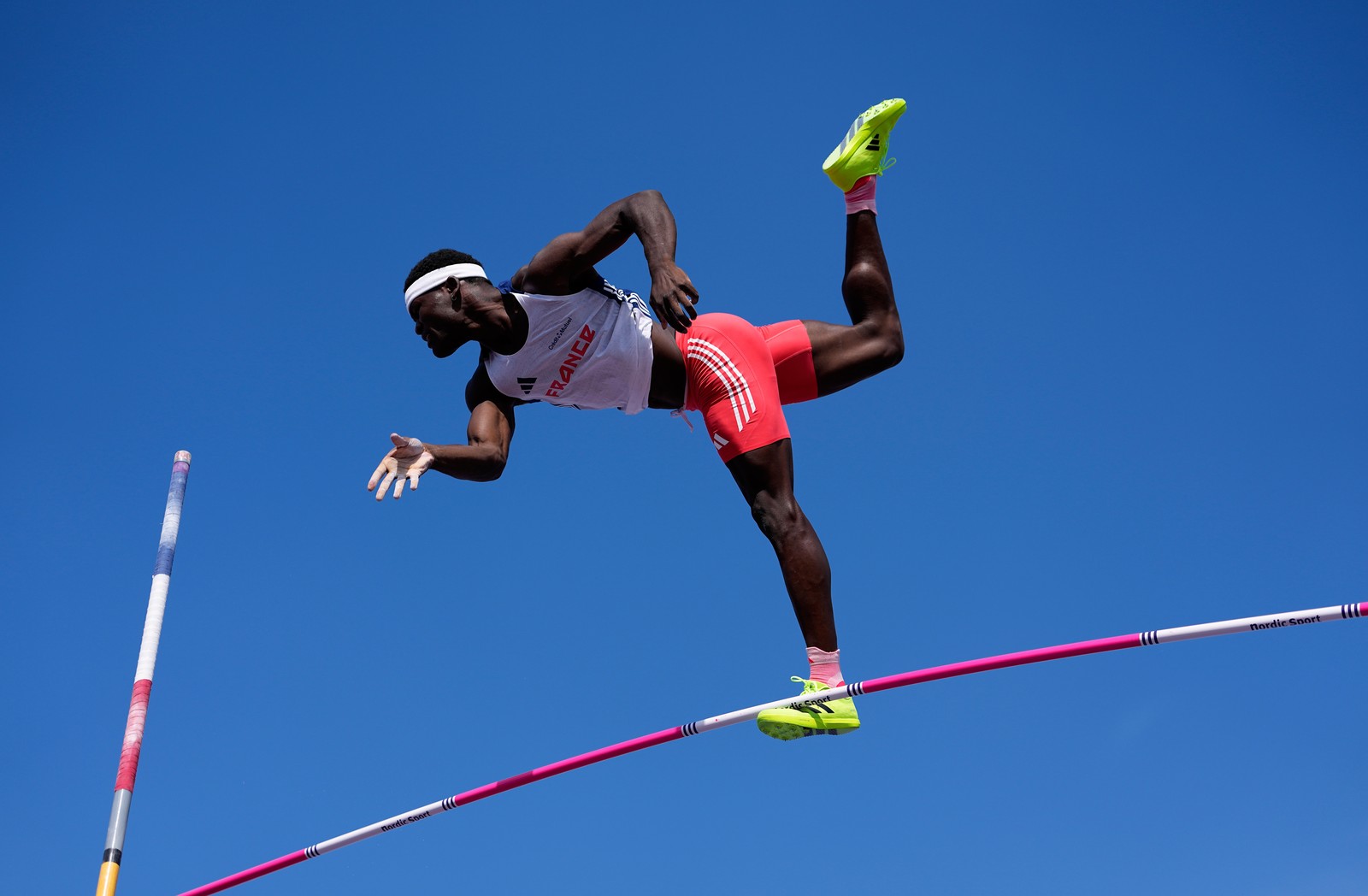 A track athlete falls through the air after missing a pole vault attempt.