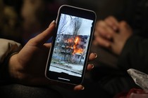 Photo of a Ukrainian refugee's smartphone, showing a video of an apartment block on fire in the city of Mykolaiv