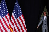 Photo of RFK Jr. walking on stage with two large American flags standing beside him