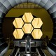 A photograph of a technician looking at the James Webb Space Telescope's gold-covered mirrors